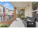 Charming covered balcony featuring brick accents, black metal railing, bench seating, and an American flag at 1670 S Deframe St # B2, Lakewood, CO 80228