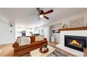 Cozy living room featuring a fireplace, ceiling fan, and an open view into the kitchen and dining area at 12201 N Holly Way, Brighton, CO 80602