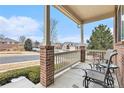 Inviting front porch featuring brick columns, railing and comfortable seating area at 2835 S Jebel Way, Aurora, CO 80013