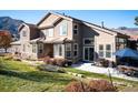 Spacious two-story home featuring stone accents, a patio with outdoor seating, and lush landscaping at 16226 River Haven Way, Morrison, CO 80465