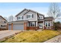 Inviting two-story home with a three-car garage, well-kept lawn, and charming front porch with seating at 6071 Russell Ln, Arvada, CO 80403