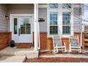 Welcoming front porch featuring rocking chairs, brick accents, and a charming entrance at 6071 Russell Ln, Arvada, CO 80403