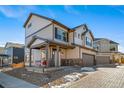 Two-story house with beige and brown siding, a two-car garage, and a paved driveway at 16142 E 111Th Dr, Commerce City, CO 80022