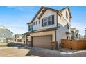 Two-story house with beige and brown siding, a two-car garage, and a paved driveway at 16142 E 111Th Dr, Commerce City, CO 80022