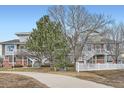 View of the townhouse exterior, showcasing trees, a white fence, and outdoor space at 9139 W 50Th Ln # 204, Arvada, CO 80002