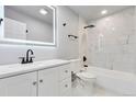 Modern bathroom featuring a white vanity, sleek black fixtures, and a luxurious tiled shower at 1705 S Yuma St, Denver, CO 80223