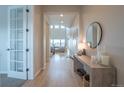 Bright entryway featuring hardwood floors, stylish console table, round mirror, and views into a spacious living area at 3008 Blithe Pt, Castle Rock, CO 80108