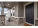 Inviting front porch featuring stone accents, a cozy seating area, and a stylish front door at 3008 Blithe Pt, Castle Rock, CO 80108