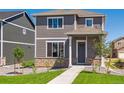 Two-story home with stone accents, gray siding, a well-manicured lawn and walkway to the front door at 28630 E 8Th St, Watkins, CO 80137