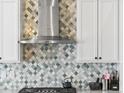 Close-up of stainless vent hood and designer backsplash in the kitchen area at 23327 E Ottawa Dr, Aurora, CO 80016