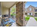 Covered front porch with stone pillar, grill, and outdoor seating area at 15362 W 66Th Ave # D, Arvada, CO 80007