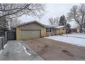 Single story home with an attached garage and snow covered yard at 306 S Newport Way, Denver, CO 80224