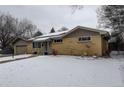 Ranch-style home featuring a brick facade and snow covered yard at 306 S Newport Way, Denver, CO 80224