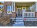 Inviting front porch with brick accents, a decorative wreath, and ample space for seating at 2572 Iola St, Aurora, CO 80010