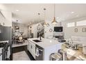 Modern kitchen featuring an island with sleek countertops and a dining area, flowing into a living room space at 2572 Iola St, Aurora, CO 80010