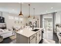 Open-concept kitchen island with pendant lights flowing into a cozy living space and outdoor patio at 2572 Iola St, Aurora, CO 80010