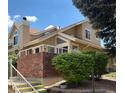Inviting two-story home featuring a brick retaining wall, white railing, and lush landscaping at 2136 S Scranton Way, Aurora, CO 80014