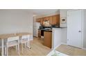 Bright kitchen with wooden cabinets, a white refrigerator, and an adjacent dining area with table and chairs at 1140 N Downing St # 303, Denver, CO 80218