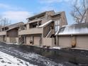 Exterior view of multi-level townhome showcasing attached garages, neutral siding, and multiple windows at 6700 W 11Th Ave # 103, Lakewood, CO 80214