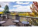 A spacious outdoor deck featuring comfortable seating with a scenic view of a peaceful lake and distant mountains at 13943 W 87Th Ln, Arvada, CO 80005