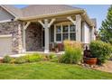 Inviting front porch, beautiful landscaping, and stacked stone accents at 13943 W 87Th Ln, Arvada, CO 80005
