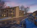 Snow covered exterior of condo building with street view and signage at dusk at 400 Zang St # 1-105, Lakewood, CO 80228