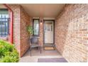 Charming, covered front entry with a brick wall, a chair and a 'Welcome' mat at 8040 W 78Th Way, Arvada, CO 80005