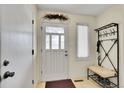 Bright foyer with white door, bench and coat rack, tile floor and a window at 8040 W 78Th Way, Arvada, CO 80005