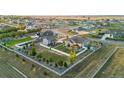 Beautifully landscaped property with white fencing, lush green lawns, fire pit area, and mature trees at 10080 E 160Th Pl, Brighton, CO 80602