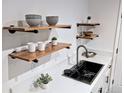 White kitchen with wooden shelves and a black sink at 9050 Cody Ct, Broomfield, CO 80021