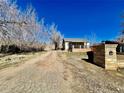 A home featuring a long dirt driveway, a quaint porch, and mature trees at 2561 W Dartmouth Ave, Denver, CO 80236