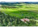 Serene property featuring a paved driveway winding through a forest to a large home with a 3-car garage at 15533 S Perry Park Rd, Palmer Lake, CO 80133