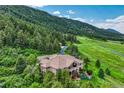 Beautiful home on a sprawling lot with a tile roof, surrounded by mature trees and landscaped gardens at 15533 S Perry Park Rd, Palmer Lake, CO 80133