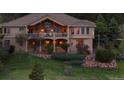 Back exterior of the home showcasing balcony, stone accents, and lush landscaping at 15533 S Perry Park Rd, Palmer Lake, CO 80133