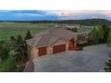 Wide view of home's driveway and three-car garage, landscaped for privacy at 15533 S Perry Park Rd, Palmer Lake, CO 80133