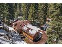 Aerial view of a wooded log cabin with a long driveway and a snowy landscape at 27802 Shadow Mountain Dr, Conifer, CO 80433