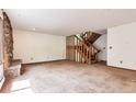 Bright living room featuring a stone fireplace, carpeted floors, and an open staircase at 4843 Silver Spruce Ln, Evergreen, CO 80439