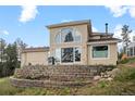 Back of house featuring a large window, brick retaining wall, and outdoor grill at 27987 Pine Grove Trl, Conifer, CO 80433
