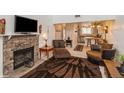 Living room with stone fireplace, television, and view into the kitchen at 8654 Decatur St # 251, Westminster, CO 80031
