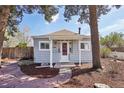 Quaint home with light blue siding, a welcoming red door, and stone pathway surrounded by mature trees at 4290 S Cherokee St, Englewood, CO 80110