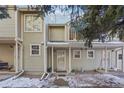 A view of the townhome exterior with covered front porches and a snowy landscape at 1818 S Quebec Way # 11-3, Denver, CO 80231