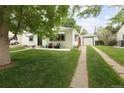 Bungalow exterior with detached garage, long driveway, and mature trees in a green lawn at 1852 S Elm St, Denver, CO 80222