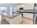 Modern kitchen with white cabinets, stainless steel appliances, an island with seating, and hard wood flooring at 7440 S Yank Ct, Littleton, CO 80127