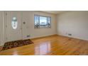 Bright living room features hardwood floors, a large window, and a welcoming front door with a decorative glass design at 11241 Ogden Dr, Northglenn, CO 80233