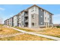 Modern apartment building featuring gray and white facade, private balconies, and manicured landscaping at 16841 Askins Loop # 101, Parker, CO 80134