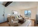 Inviting living room featuring a decorative beam, comfortable seating, and a door leading to a balcony at 16259 W 10Th Ave # J5, Golden, CO 80401