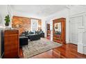 Open-concept living room with hardwood floors, exposed brick wall, and ample natural light at 1141 Adams St, Denver, CO 80206