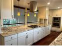 A modern kitchen with a large island, a cooktop, modern appliances, and beautiful pendant lights at 7906 W Walker Dr, Littleton, CO 80123