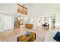 Open-concept living room with hardwood floors, vaulted ceiling, staircase, and view into the dining area at 16438 E Prentice Cir, Centennial, CO 80015