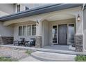 Inviting front porch with comfortable seating, stone pillars, and an elegant entry door creates a welcoming first impression at 14993 W 55Th Dr, Golden, CO 80403